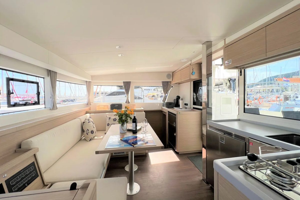 The saloon of Wind Seeker, table set, galley to starboard and the marina through the windows